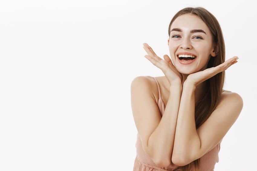 Beautiful and healthy charming woman with natural beauty holding palms near jawline